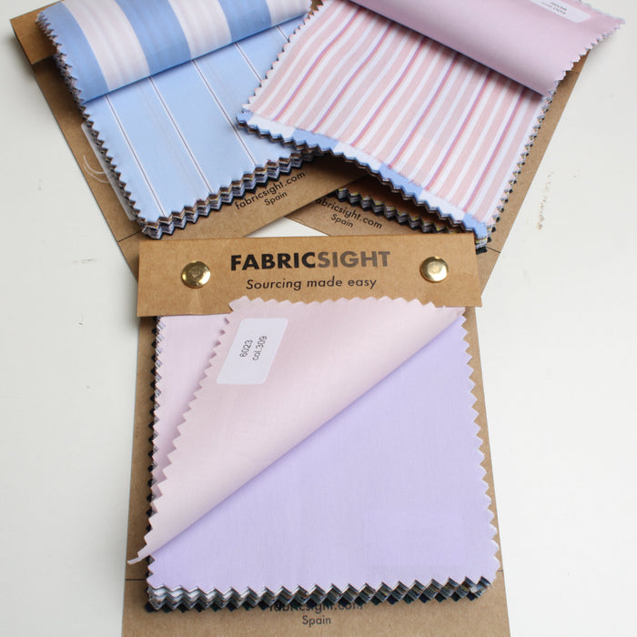 Fabricsight fabric swatch book showing multiple fabric samples in pastel colors, including light blue and white stripes, pink and white stripes, and light purple, displayed on a white background.