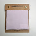 A Fabricsight brand fabric swatch card showing a light lavender purple fabric sample, mounted on a brown cardboard backing with gold metal grommets.